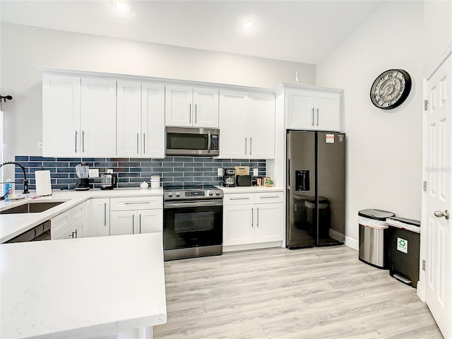 kitchen with sink, appliances with stainless steel finishes, light hardwood / wood-style flooring, tasteful backsplash, and white cabinetry