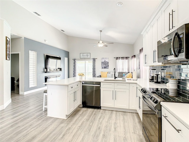 kitchen featuring kitchen peninsula, ceiling fan, appliances with stainless steel finishes, light hardwood / wood-style floors, and tasteful backsplash