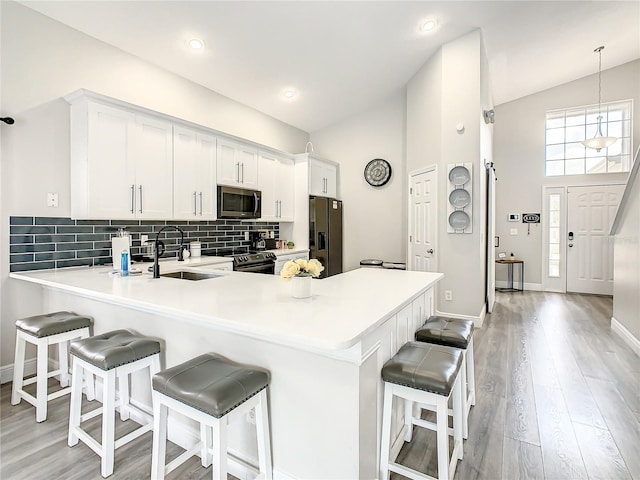 kitchen featuring pendant lighting, stainless steel appliances, a breakfast bar area, light wood-type flooring, and sink