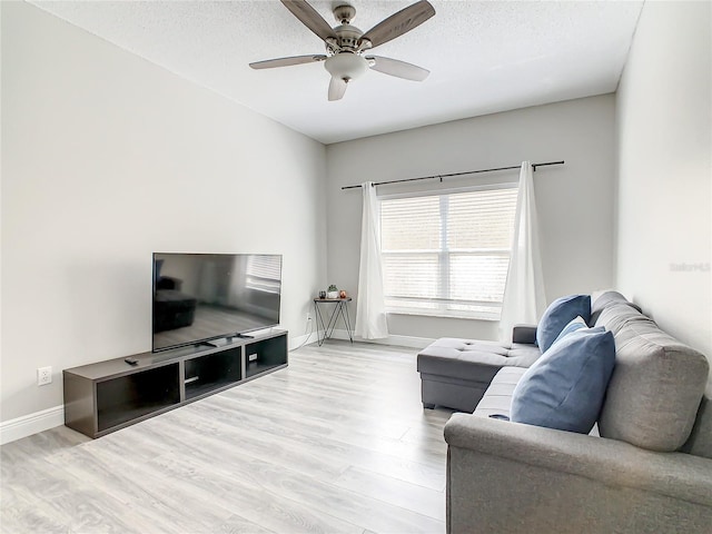 living room featuring a textured ceiling, ceiling fan, and light wood-type flooring