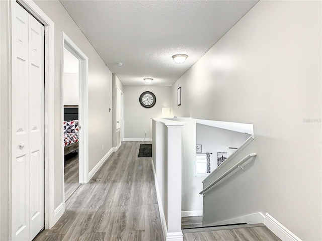 hallway with a textured ceiling and light hardwood / wood-style flooring