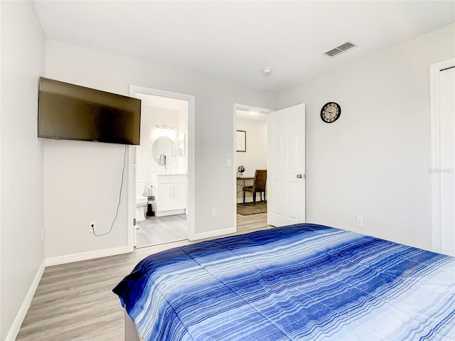 bedroom featuring light hardwood / wood-style floors and ensuite bath