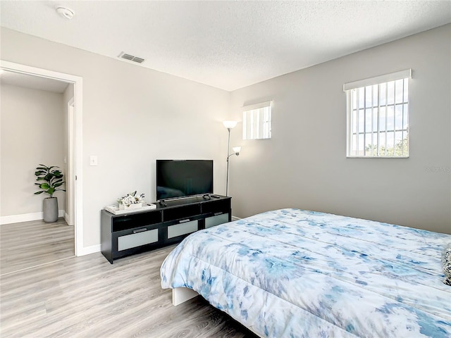 bedroom featuring light hardwood / wood-style floors and a textured ceiling