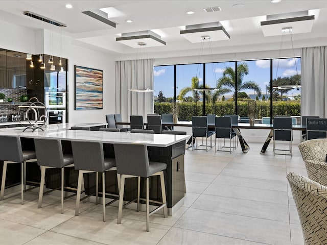 kitchen featuring a kitchen bar, pendant lighting, and light tile floors