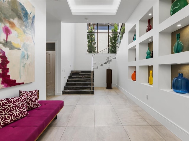 interior space featuring a raised ceiling, light tile flooring, and built in shelves