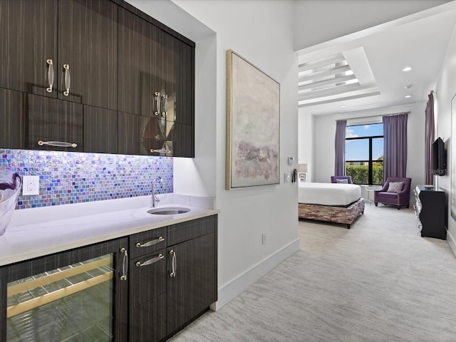 interior space with backsplash, sink, light carpet, beverage cooler, and dark brown cabinetry