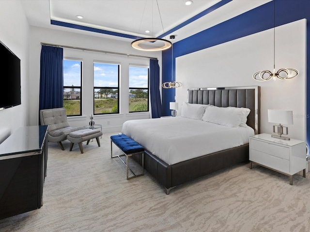 bedroom with light carpet and a tray ceiling