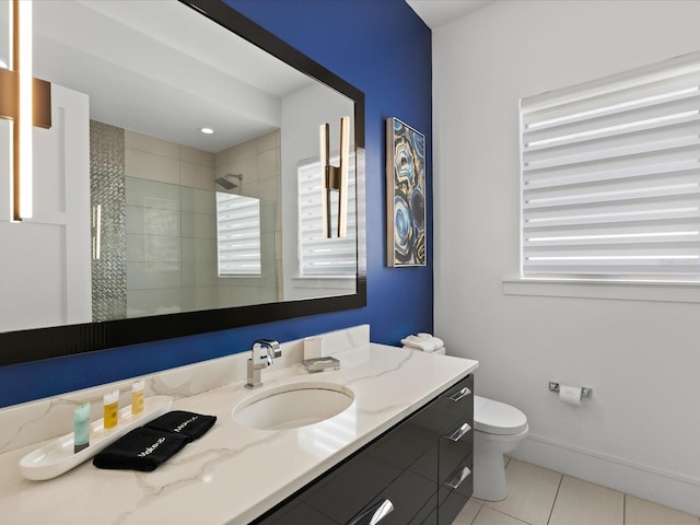 bathroom with a wealth of natural light, toilet, large vanity, and tile flooring