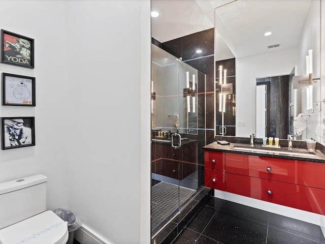 bathroom with toilet, large vanity, tile floors, and a shower with shower door