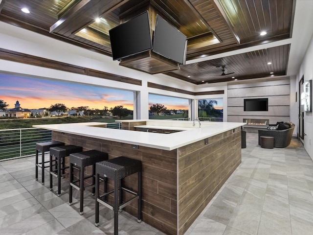 exterior space with light tile flooring, wooden ceiling, a kitchen island with sink, and a breakfast bar