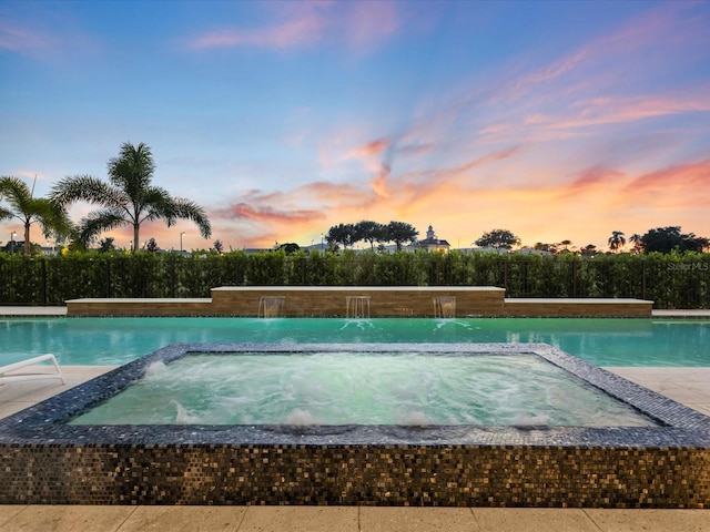 pool at dusk featuring pool water feature