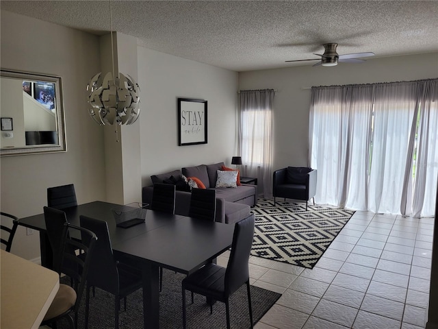 tiled dining space with a textured ceiling and ceiling fan