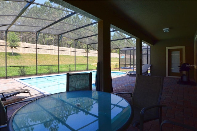 view of pool with a yard, glass enclosure, and a patio