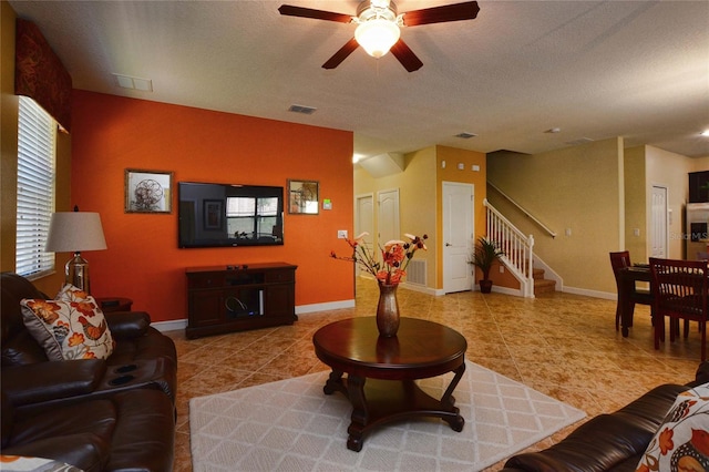 living room featuring light tile floors, ceiling fan, and a textured ceiling