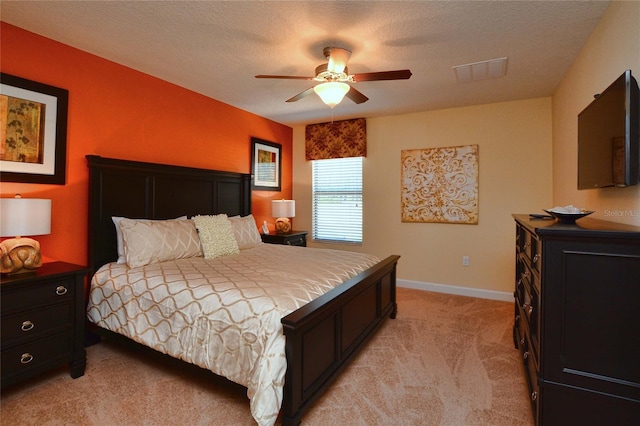 bedroom featuring a textured ceiling, ceiling fan, and light colored carpet