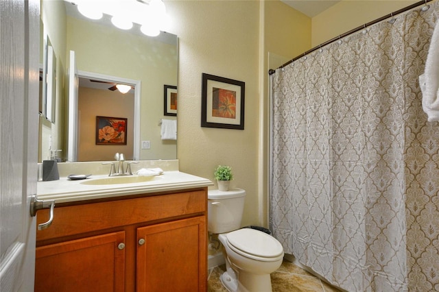 bathroom featuring ceiling fan, tile flooring, vanity with extensive cabinet space, and toilet