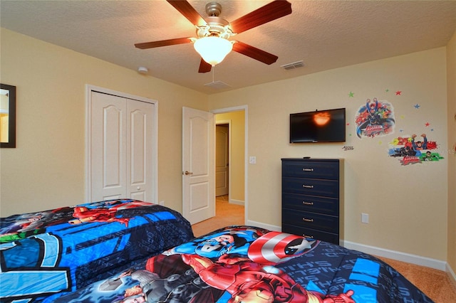 bedroom featuring light colored carpet, a closet, ceiling fan, and a textured ceiling