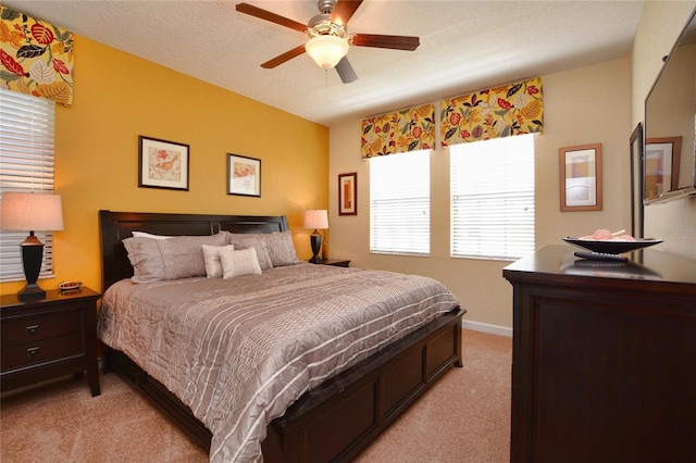 bedroom featuring a textured ceiling, light colored carpet, and ceiling fan