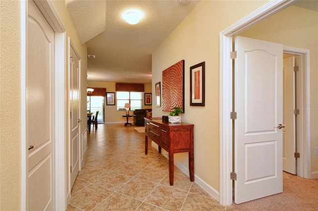 corridor featuring light carpet and a textured ceiling