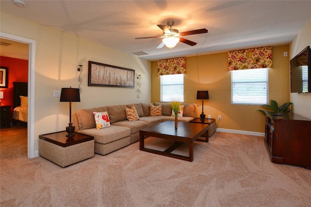 living room featuring light colored carpet, ceiling fan, and a textured ceiling