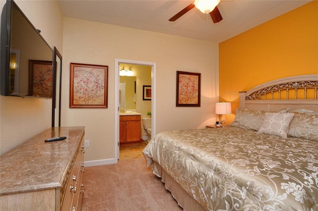 bedroom featuring ensuite bath, light colored carpet, and ceiling fan