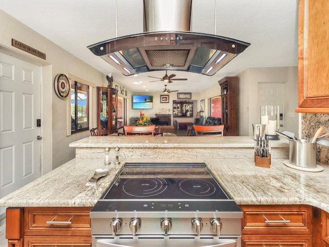 kitchen with island exhaust hood, ceiling fan, and light stone countertops