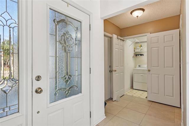 tiled foyer entrance featuring washer / dryer and a textured ceiling