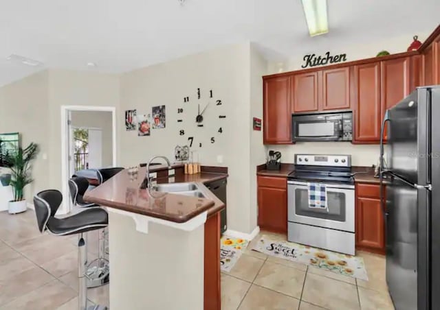 kitchen featuring a kitchen bar, stainless steel appliances, light tile floors, and sink