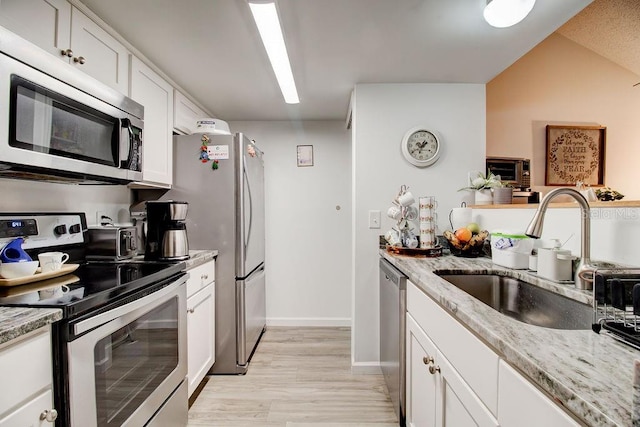 kitchen with light stone countertops, sink, white cabinets, and appliances with stainless steel finishes