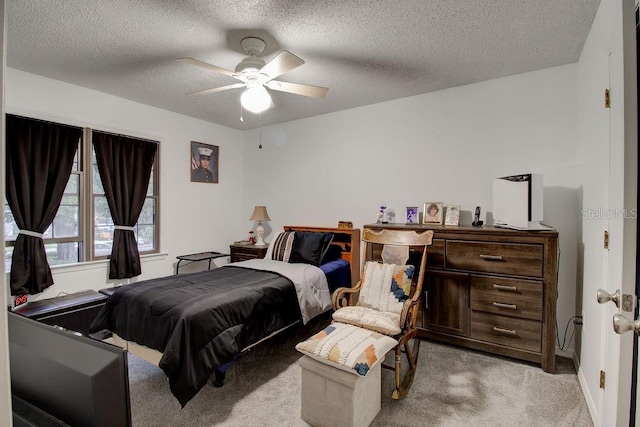 bedroom with ceiling fan, light carpet, and a textured ceiling