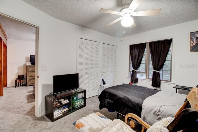 carpeted bedroom featuring ceiling fan and a textured ceiling