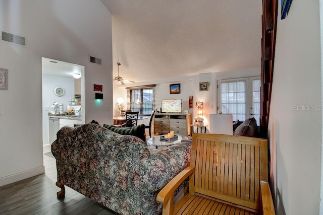 living room with ceiling fan, wood-type flooring, and a high ceiling