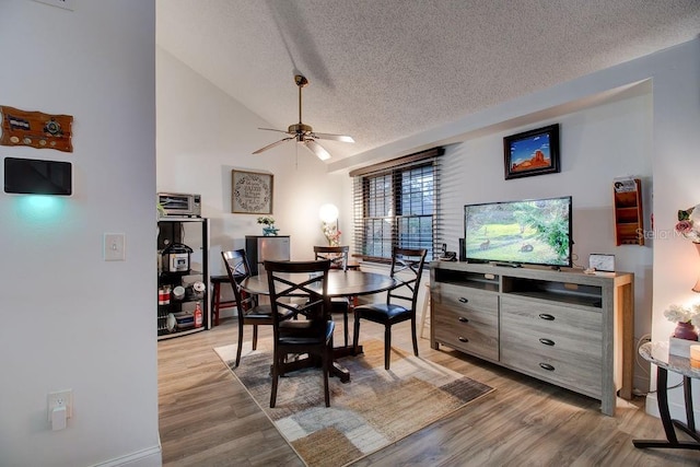 dining room featuring vaulted ceiling, ceiling fan, a textured ceiling, and hardwood / wood-style flooring