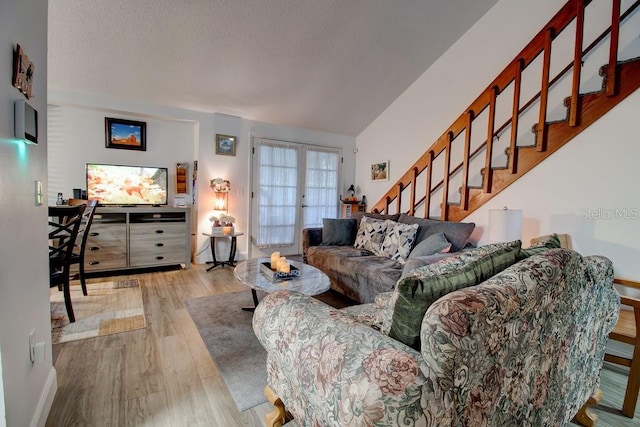 living room with vaulted ceiling, light wood-type flooring, and french doors