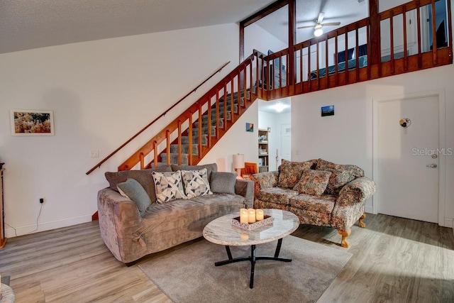 living room featuring light hardwood / wood-style floors, high vaulted ceiling, and ceiling fan