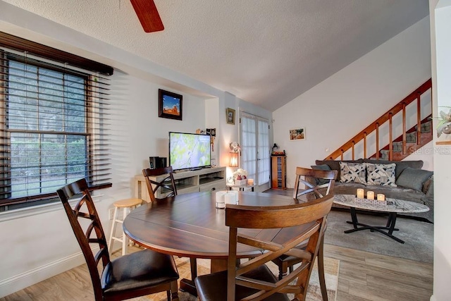 dining area with a textured ceiling, ceiling fan, light hardwood / wood-style flooring, and lofted ceiling