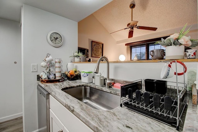 kitchen with dishwasher, light stone counters, lofted ceiling, and sink