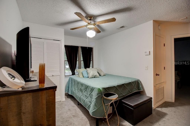 carpeted bedroom featuring a textured ceiling, a closet, and ceiling fan