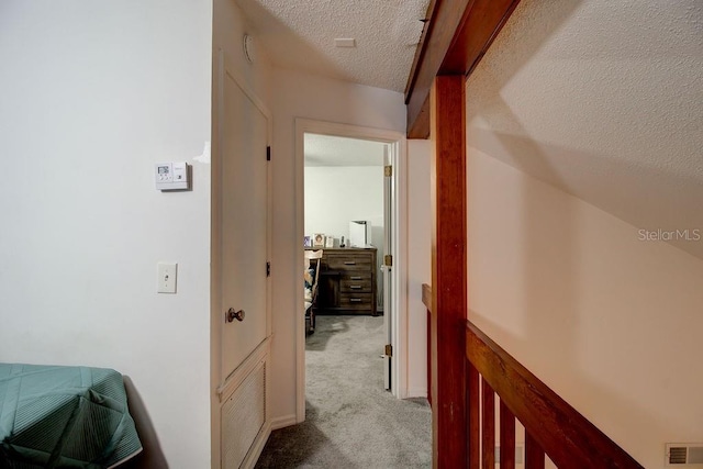 corridor with light colored carpet and a textured ceiling