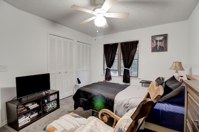 carpeted bedroom with ceiling fan, a textured ceiling, and multiple closets