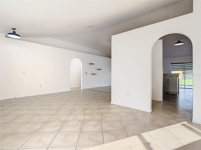 tiled empty room featuring lofted ceiling