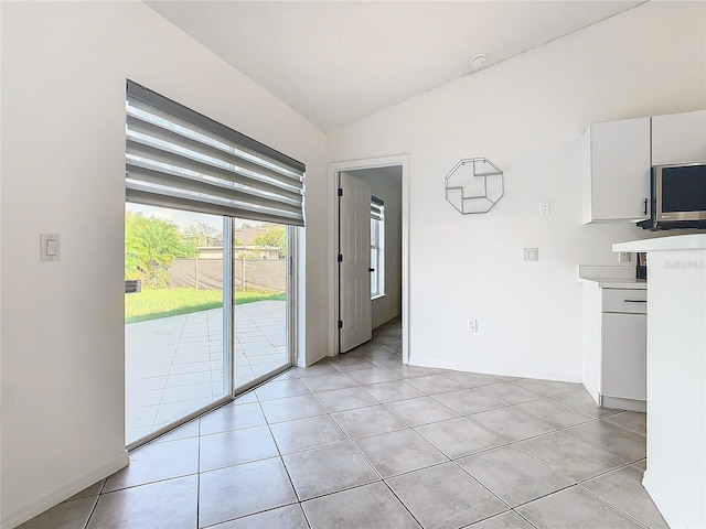 interior space with lofted ceiling and light tile patterned flooring