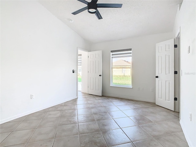 tiled spare room with ceiling fan, a textured ceiling, and lofted ceiling