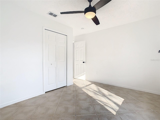 unfurnished bedroom featuring a closet, ceiling fan, a textured ceiling, and light tile patterned flooring