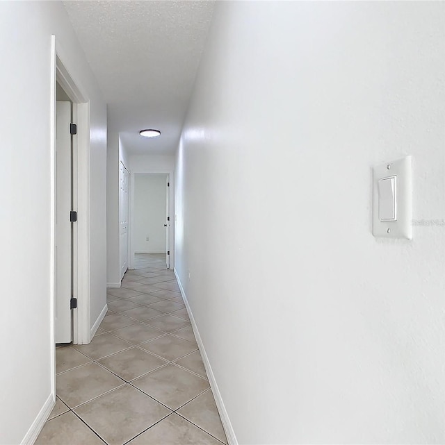 hall featuring a textured ceiling and light tile patterned flooring