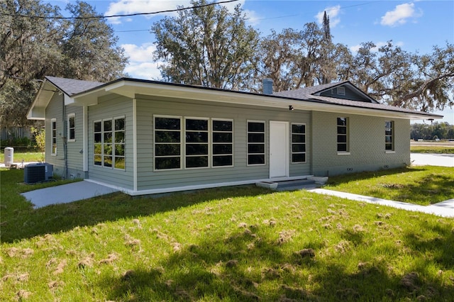 rear view of house featuring central AC unit, a yard, and a patio area