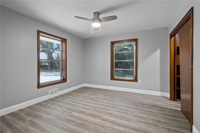 empty room with a textured ceiling, ceiling fan, and light hardwood / wood-style flooring