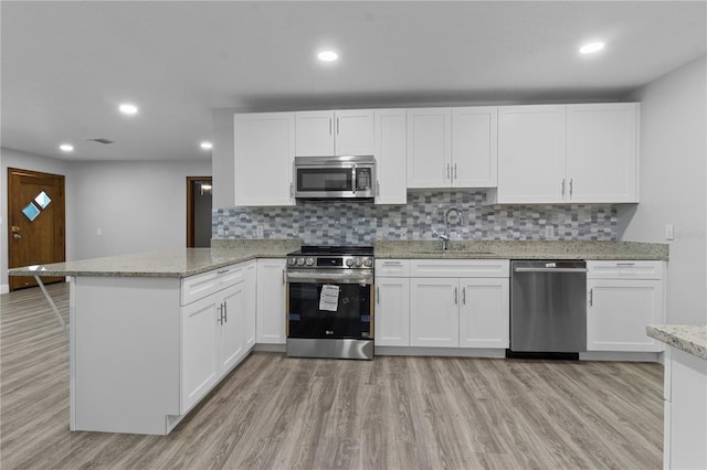 kitchen featuring light wood-type flooring, stainless steel appliances, and white cabinetry