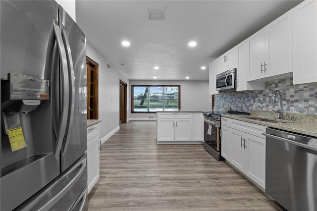 kitchen featuring white cabinets, light hardwood / wood-style floors, light stone counters, and stainless steel appliances