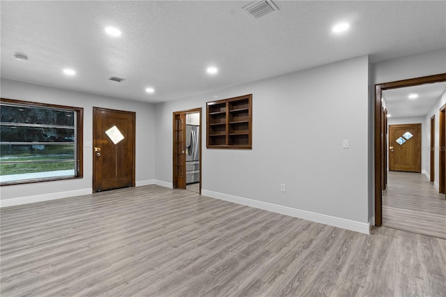 entrance foyer featuring a textured ceiling and light wood-type flooring